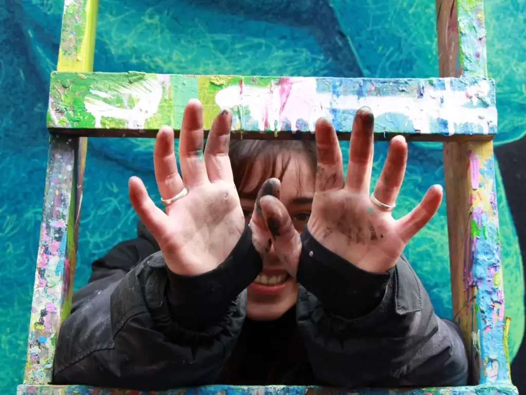 Joven extendiendo las manos con pintura.