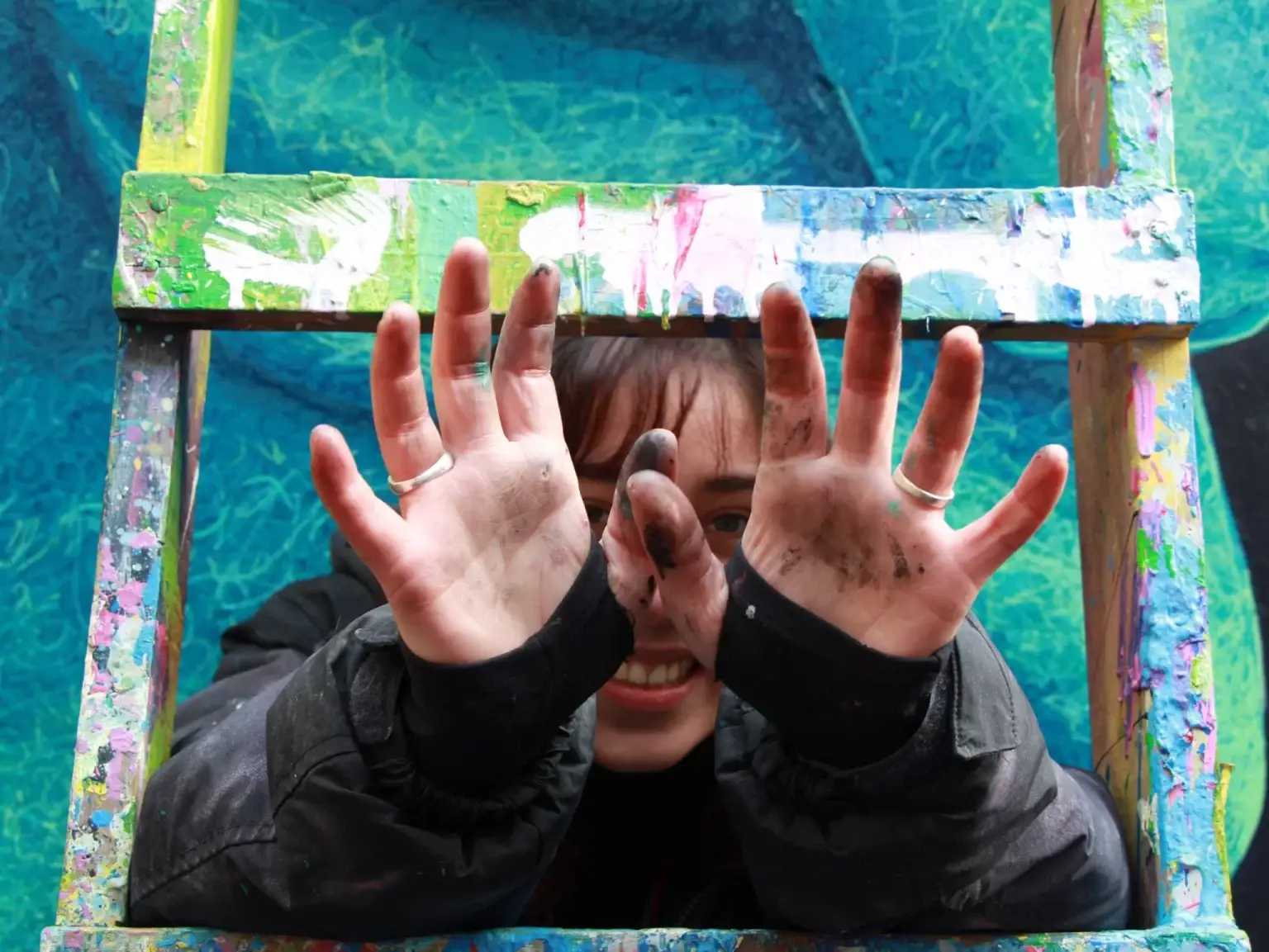 Joven extendiendo las manos con pintura.